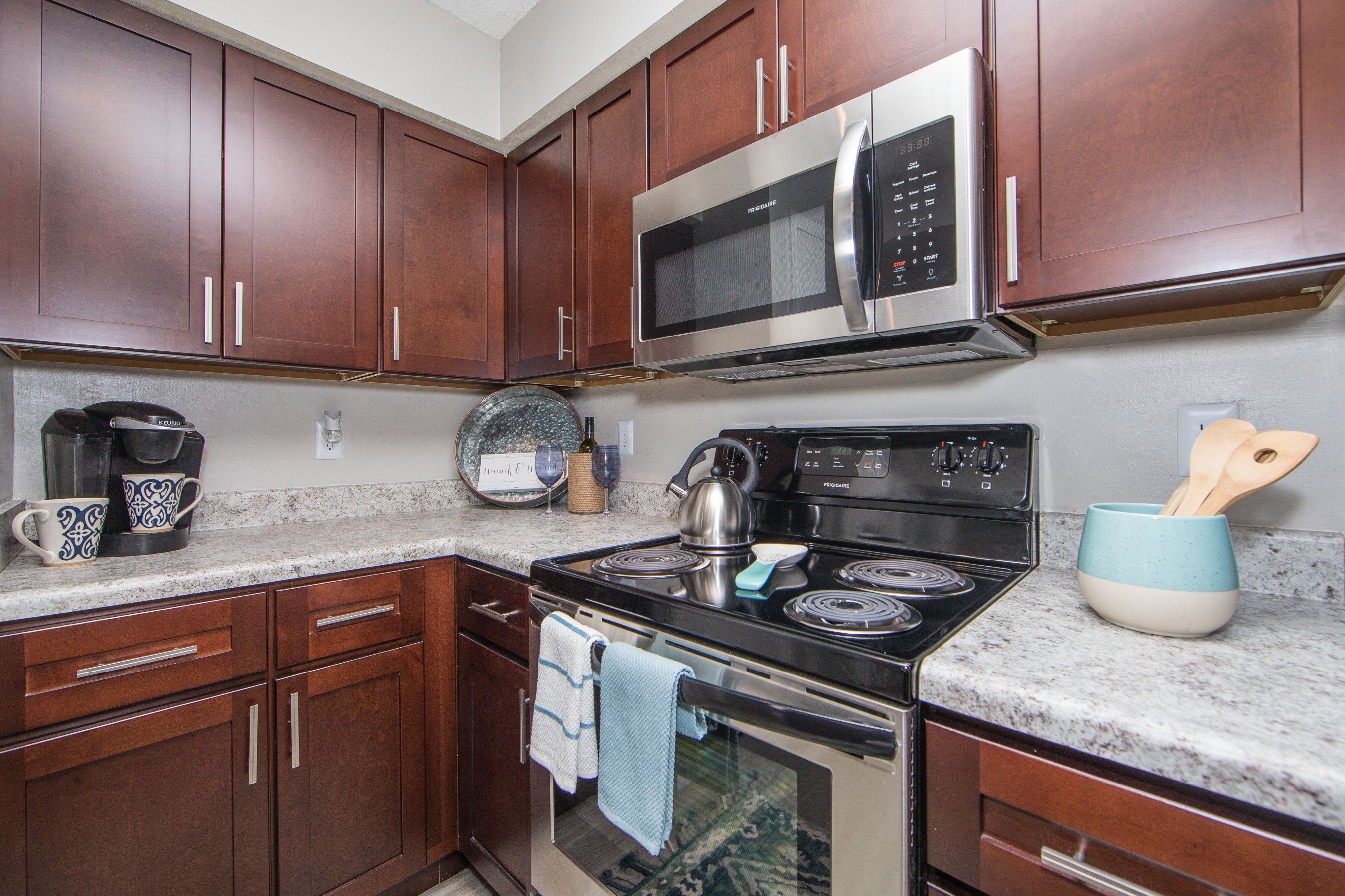 Kitchen with granite countertops stainless microwave and electric stove at St. Croix Apartments in Virginia Beach VA
